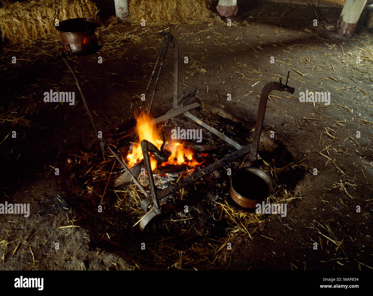 Foyer Central, feu de bois, feu chiens & metal casseroles à l'intérieur de la MOEL y Âge du Fer Gerddi à Butser maison ancienne ferme, Hampshire, Royaume-Uni. Banque D'Images