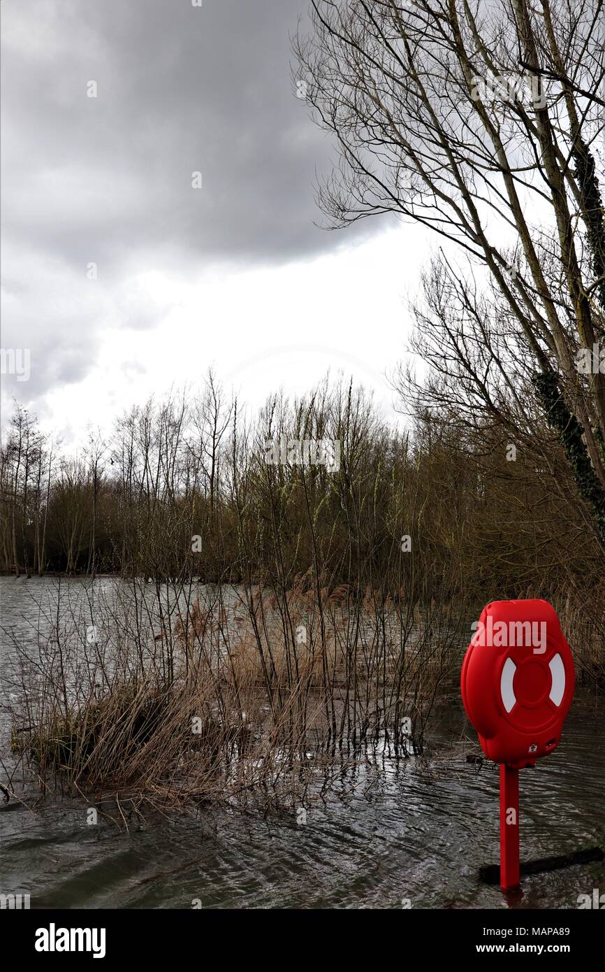 Une bouée dans une case rouge lumineux donnant sur un lac dans le Suffolk inondées Needham UK Banque D'Images