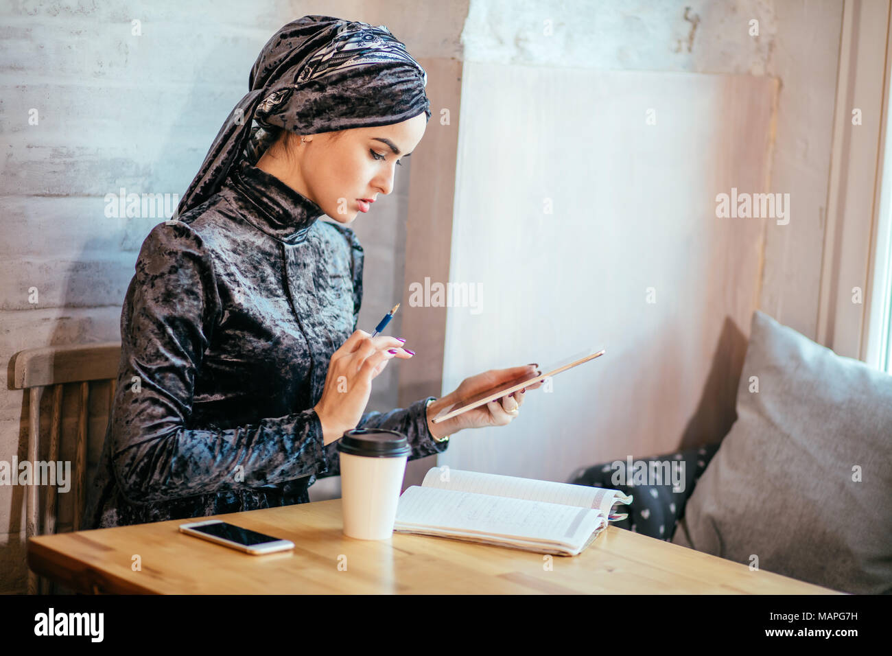 Travailler avec les femmes musulmanes en comprimé et boire un café dans un café Banque D'Images