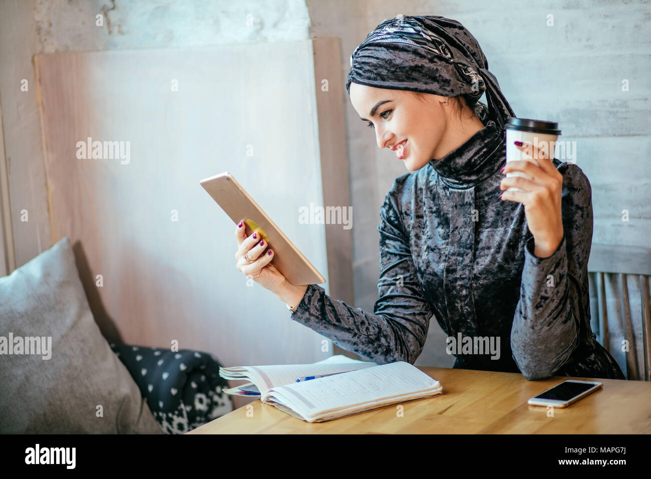 Travailler avec les femmes musulmanes en comprimé et boire un café dans un café Banque D'Images