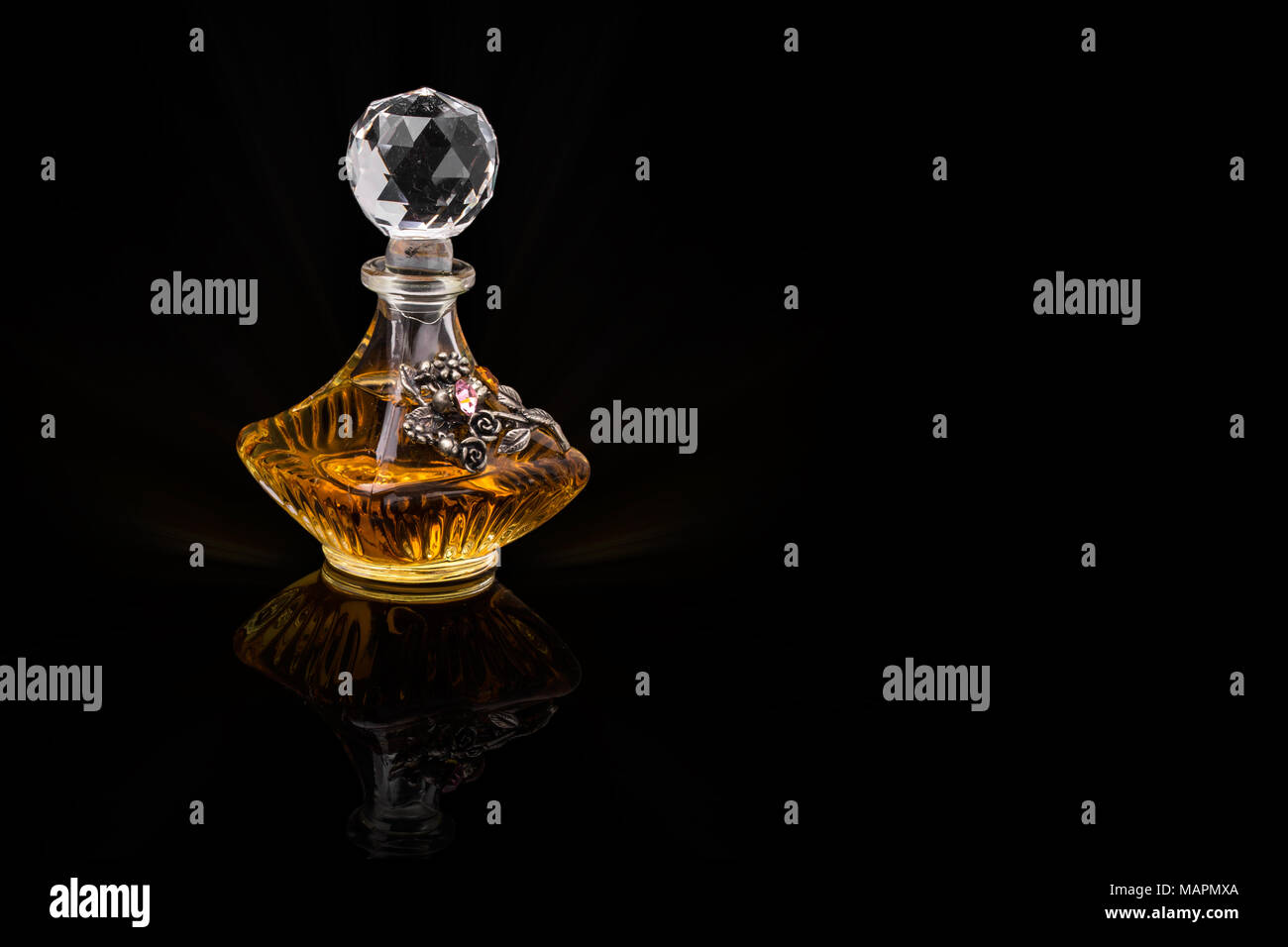 Gros plan de luxe traditionnel arabe Oud Parfum d'huile dans un beau bol en verre de cristal clair fait main et bouteille compte-gouttes en verre isolé sur Black Banque D'Images
