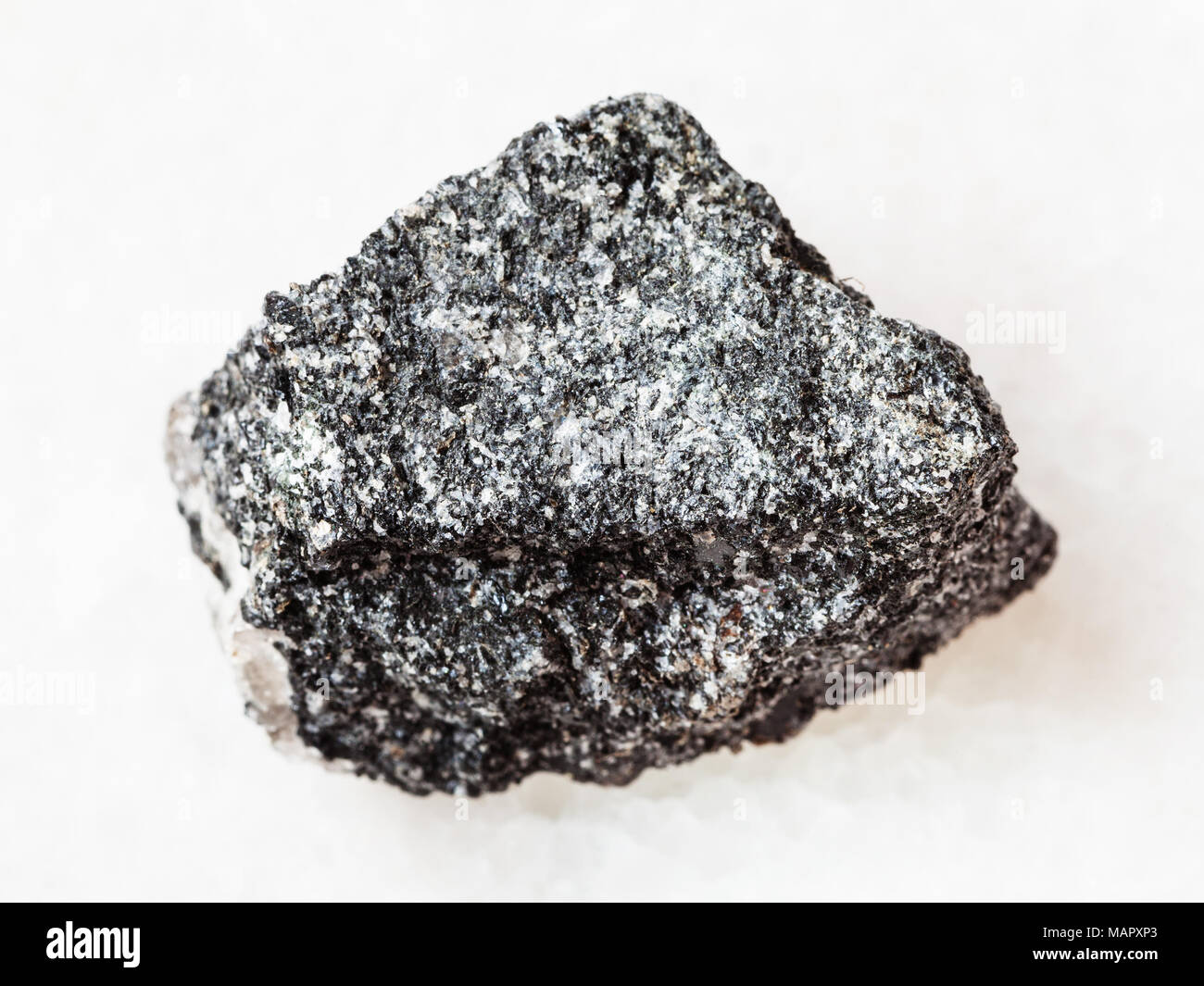 La prise de vue macro des eaux minérales naturelles rock specimen - amphibolite rugueux pierre sur fond de marbre blanc Banque D'Images