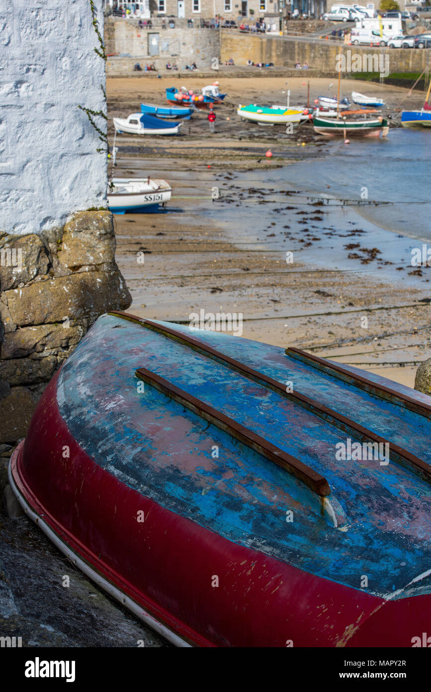 Un petit vieux bateau de pêche et tournée vers la gauche sur une cale dans le village de pêcheurs de Cornouailles mousehole sur la côte de Cornwall. bateau à rames sur la plage Banque D'Images