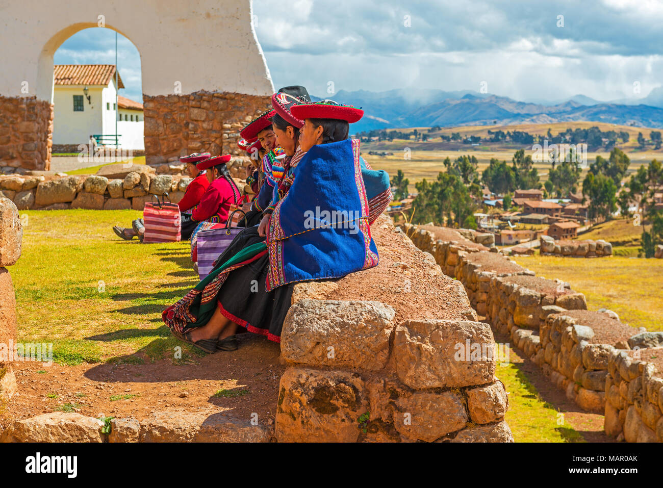 Un groupe de femmes autochtones Quechua assis sur un ancien mur Inca pendant un rassemblement social à Chincheros près de Cusco, Pérou, ville de l'Amérique du Sud. Banque D'Images