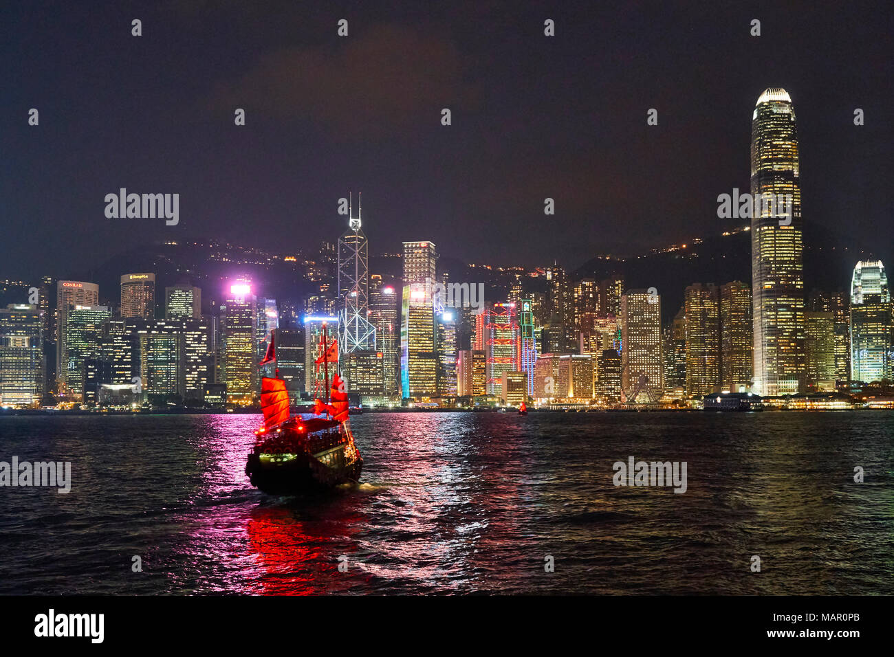 Jonque traditionnelle sur le port de Victoria avec derrière les toits de la ville illuminée la nuit, Hong Kong, Chine, Asie Banque D'Images