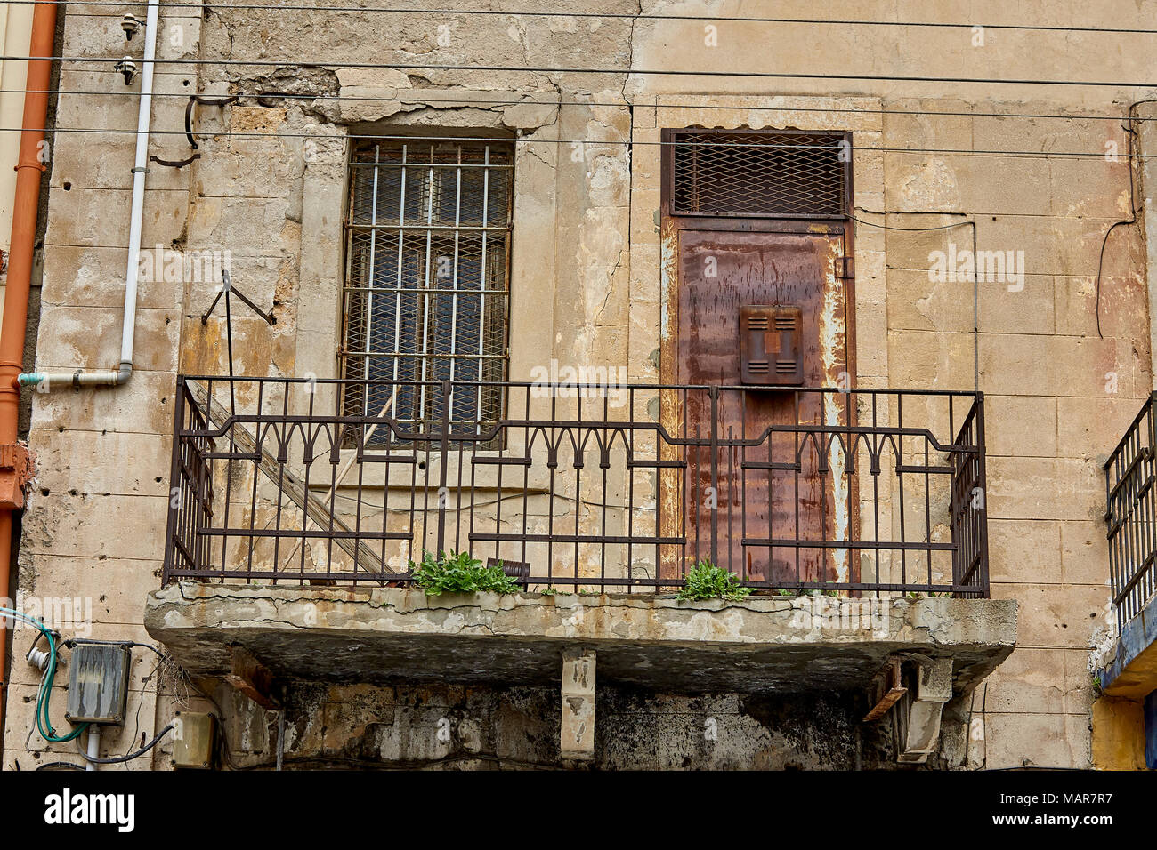 Une porte rouillée et interdit l'ouverture de la fenêtre d'un balcon en ruine Banque D'Images