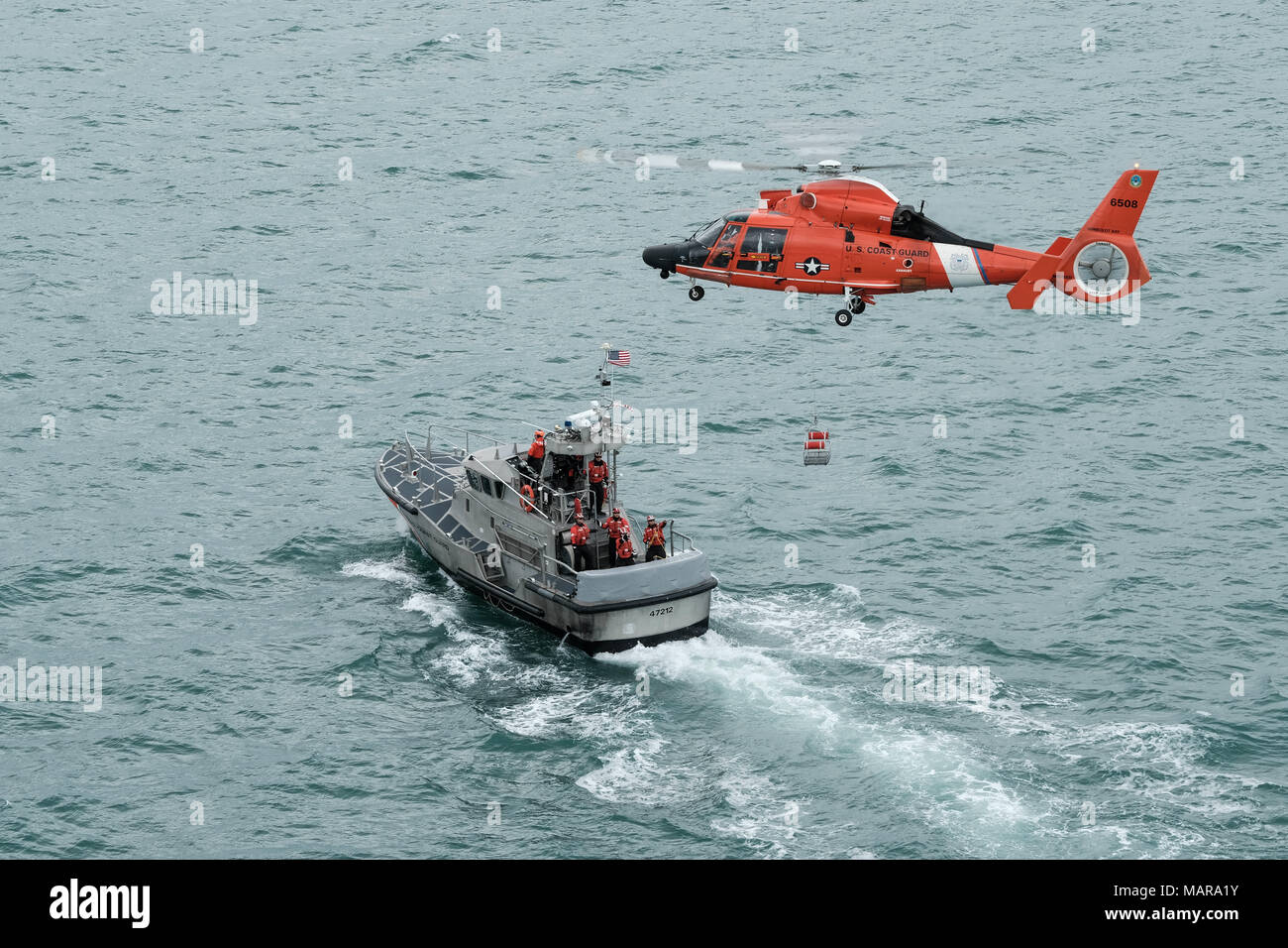 Un hélicoptère MH-65 de l'équipe de Dolphin Coast Guard Air Station Humboldt Bay abaisse une nacelle de sauvetage d'une embarcation à moteur de 47 pieds au cours de la formation de l'équipage à Eureka, Californie, le 7 mars 2018. Les équipages des hélicoptères de la Garde côtière canadienne effectuent couramment des équipages de petits bateaux avec formation de maintenir leurs qualifications et ainsi que dans le cas d'une évacuation sanitaire demande d'un bateau ou navire, les équipages sont compétents dans leurs techniques de sauvetage. (Photo de la Garde côtière canadienne par le Premier maître de Brandyn Hill) Banque D'Images