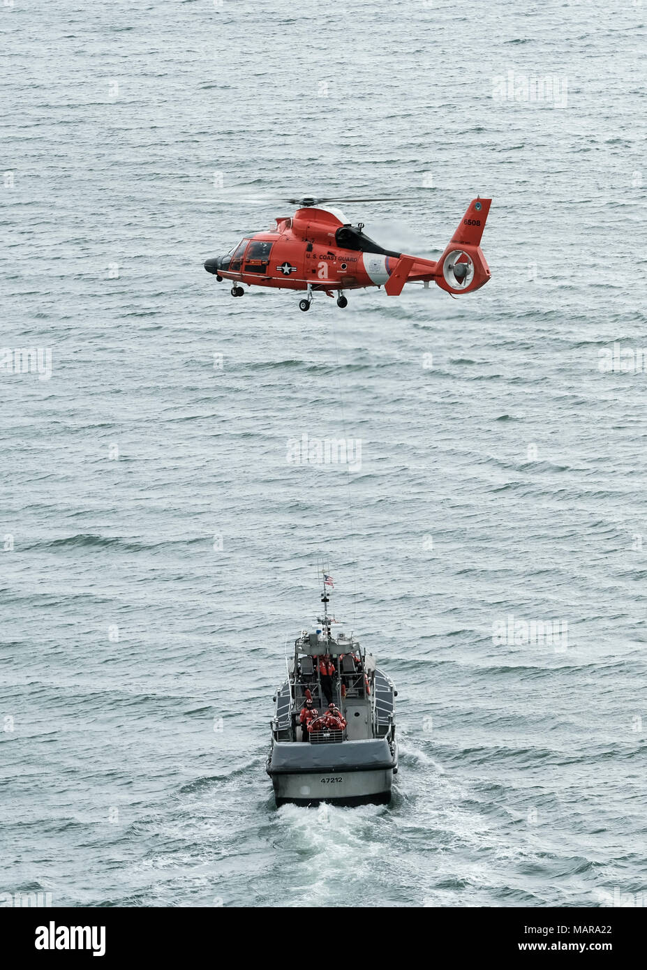 Un hélicoptère MH-65 de l'équipe de Dolphin Coast Guard Air Station Humboldt Bay plane au-dessus d'une embarcation à moteur de 47 pieds au cours de la formation de l'équipage à Eureka, Californie, le 7 mars 2018. Les équipages des hélicoptères de la Garde côtière canadienne effectuent couramment des équipages de petits bateaux avec formation de maintenir leurs qualifications et ainsi que dans le cas d'une évacuation sanitaire demande d'un bateau ou navire, les équipages sont compétents dans leurs techniques de sauvetage. Banque D'Images