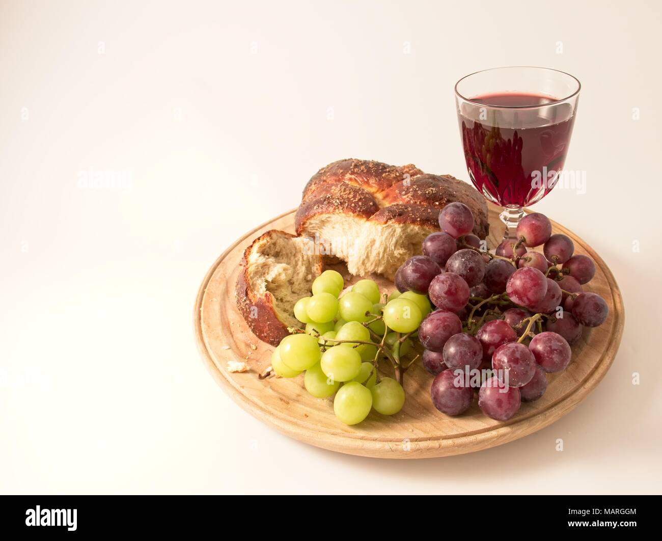 Une plaque de bois avec du pain frais, le raisin et le vin rouge. Banque D'Images