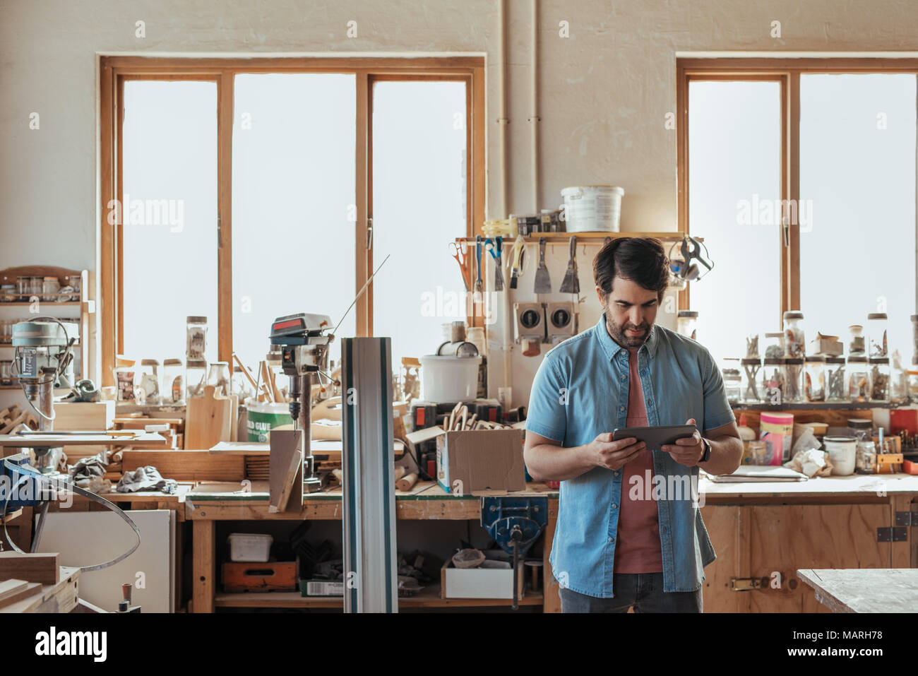 Jeune menuisier à l'aide d'une tablette numérique dans son atelier Banque D'Images