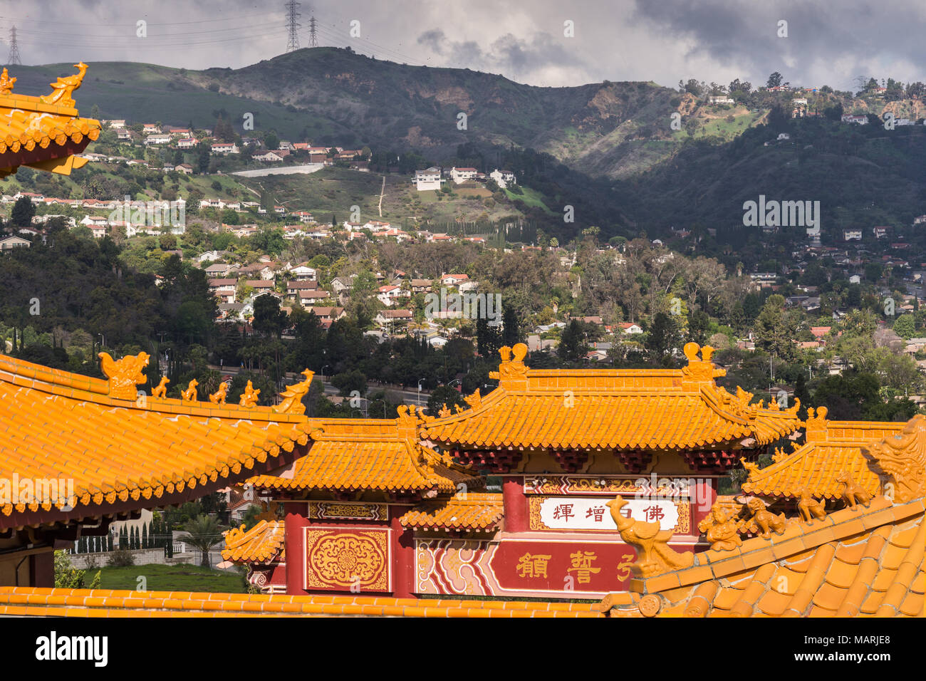 Hacienda Heights, Californie, USA - Le 23 mars 2018 : l'ocre rouge structures de toit de Hsi Lai Temple Bouddhiste sous de lourdes foncé Vert foncé avec cloudscape et collines Banque D'Images