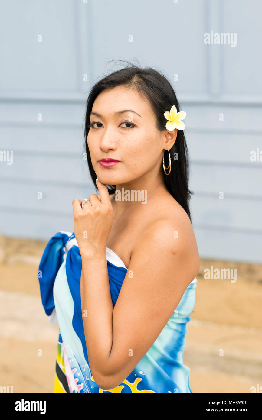 Portrait d'une jolie femme thaïlandaise. Outdoor portrait d'une femme thaïlandaise asiatique avec fleur jaune dans ses cheveux. Banque D'Images