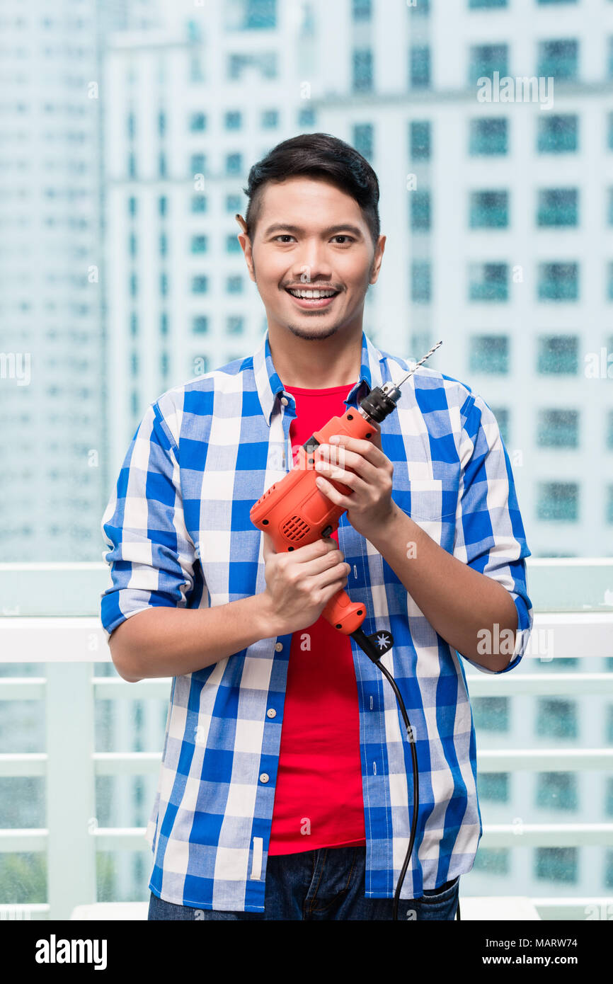 Young indonesian man avec perceuse électrique Banque D'Images
