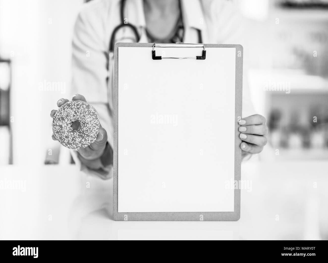 Gros plan sur femme médecin showing blank presse-papiers et donut Banque D'Images