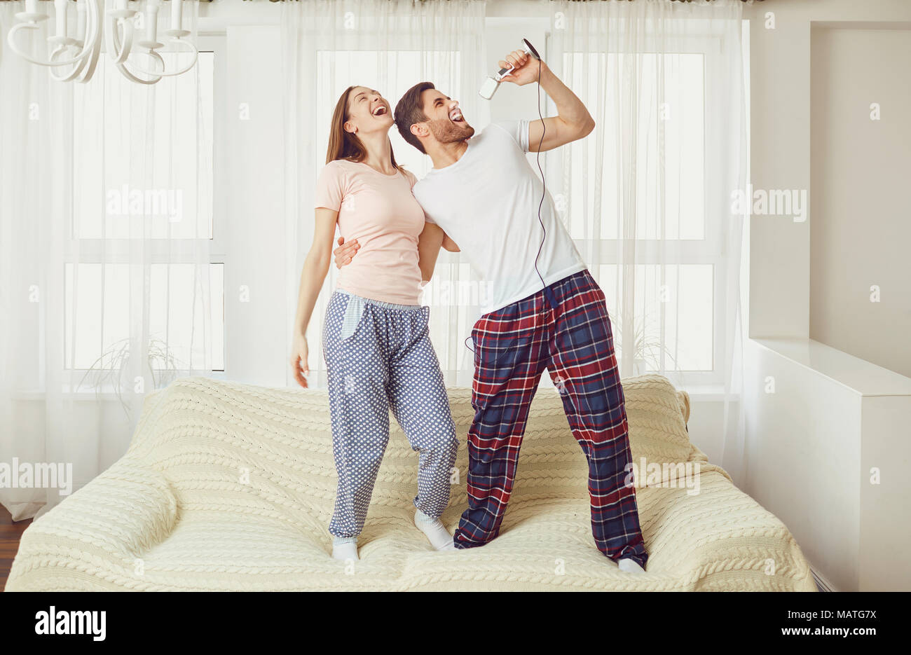 Un jeune couple avec un microphone chanter des chansons ensemble. Banque D'Images