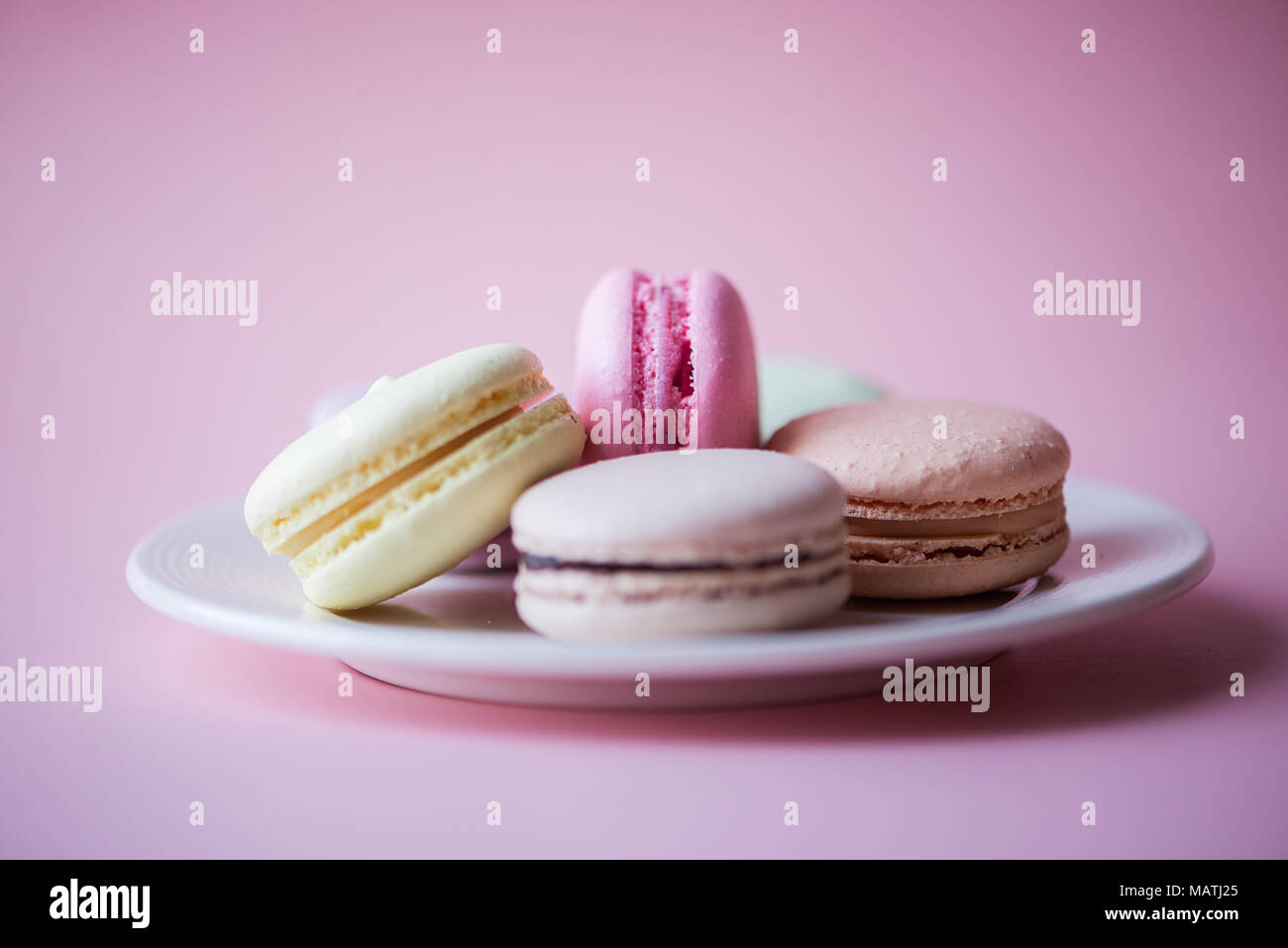 Gâteau sucré macarons français (ou macarons) avec des couleurs pastel vintage tone sur fond rose. Banque D'Images