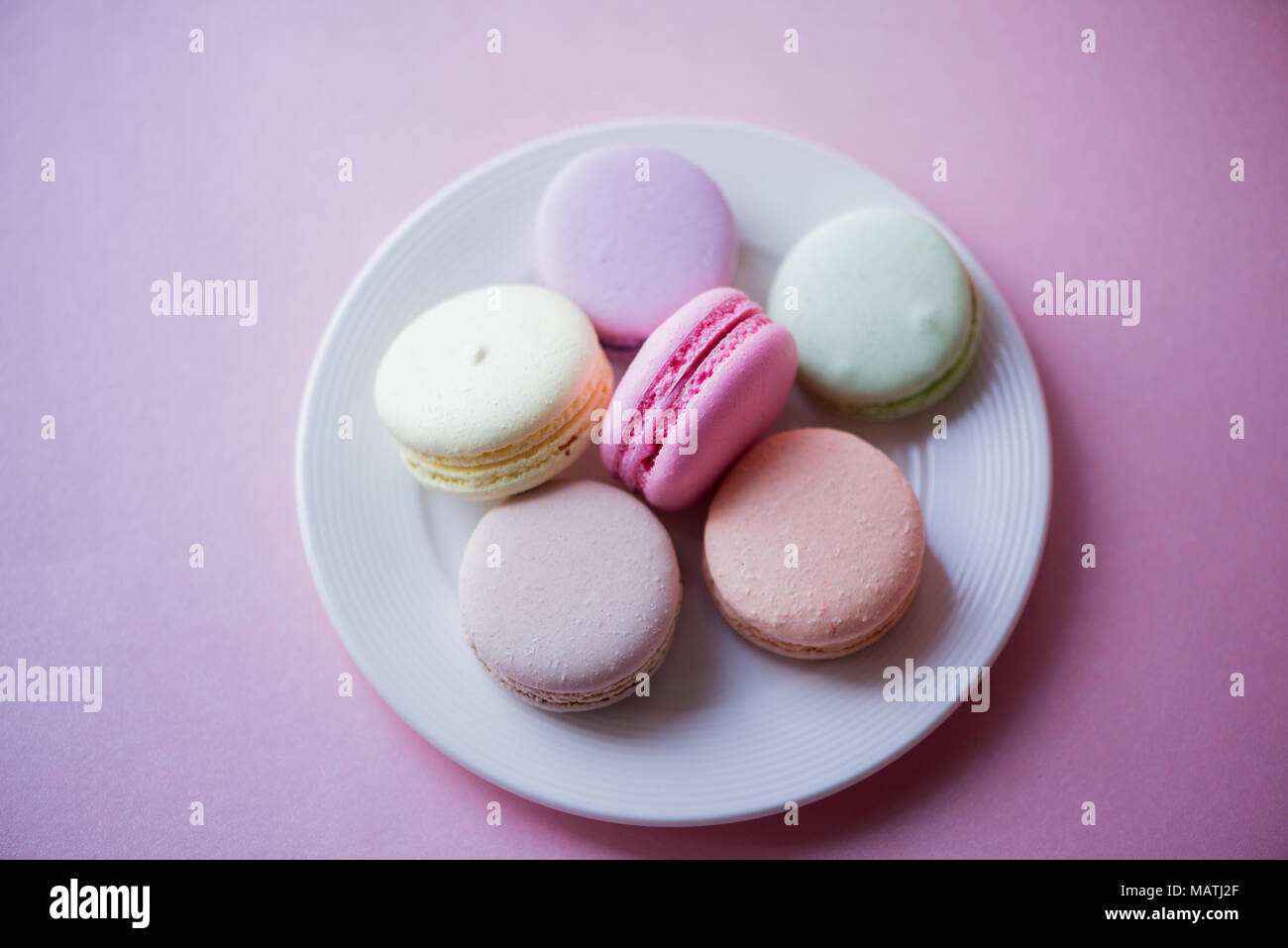 Gâteau sucré macarons français (ou macarons) avec des couleurs pastel vintage tone sur fond rose. Banque D'Images