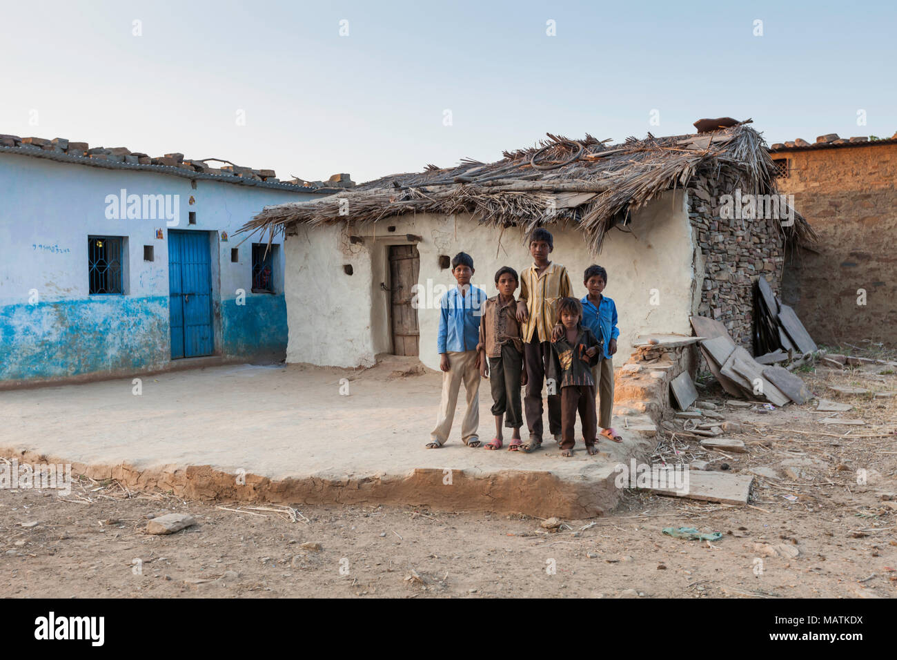 Cinq enfants de la tribu Bhil se tiennent à l'extérieur d'une maison traditionnelle près de Bhainsrorgarh, les zones rurales du Rajasthan, en Inde. Banque D'Images