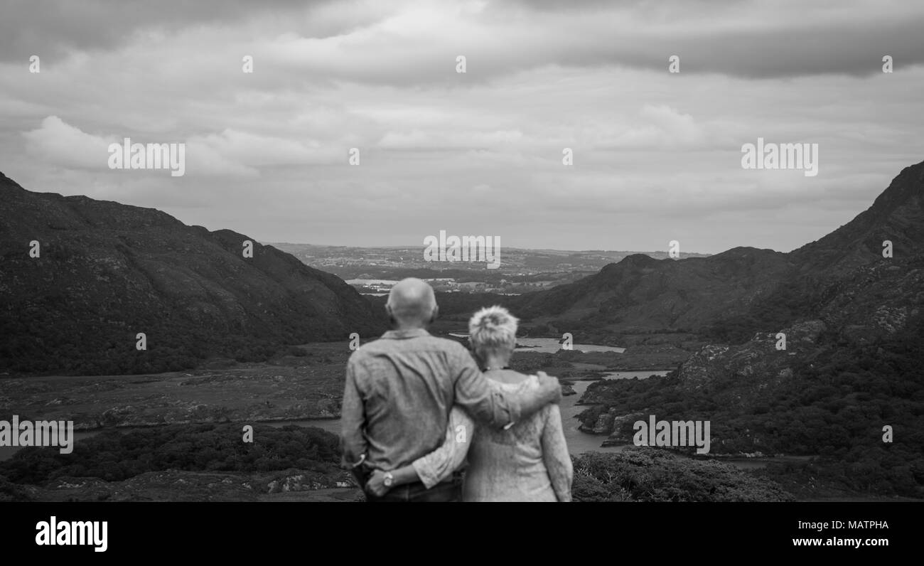 Couple regarder dehors parmi les montagnes de Kerry, bras dessus bras dessous. Banque D'Images