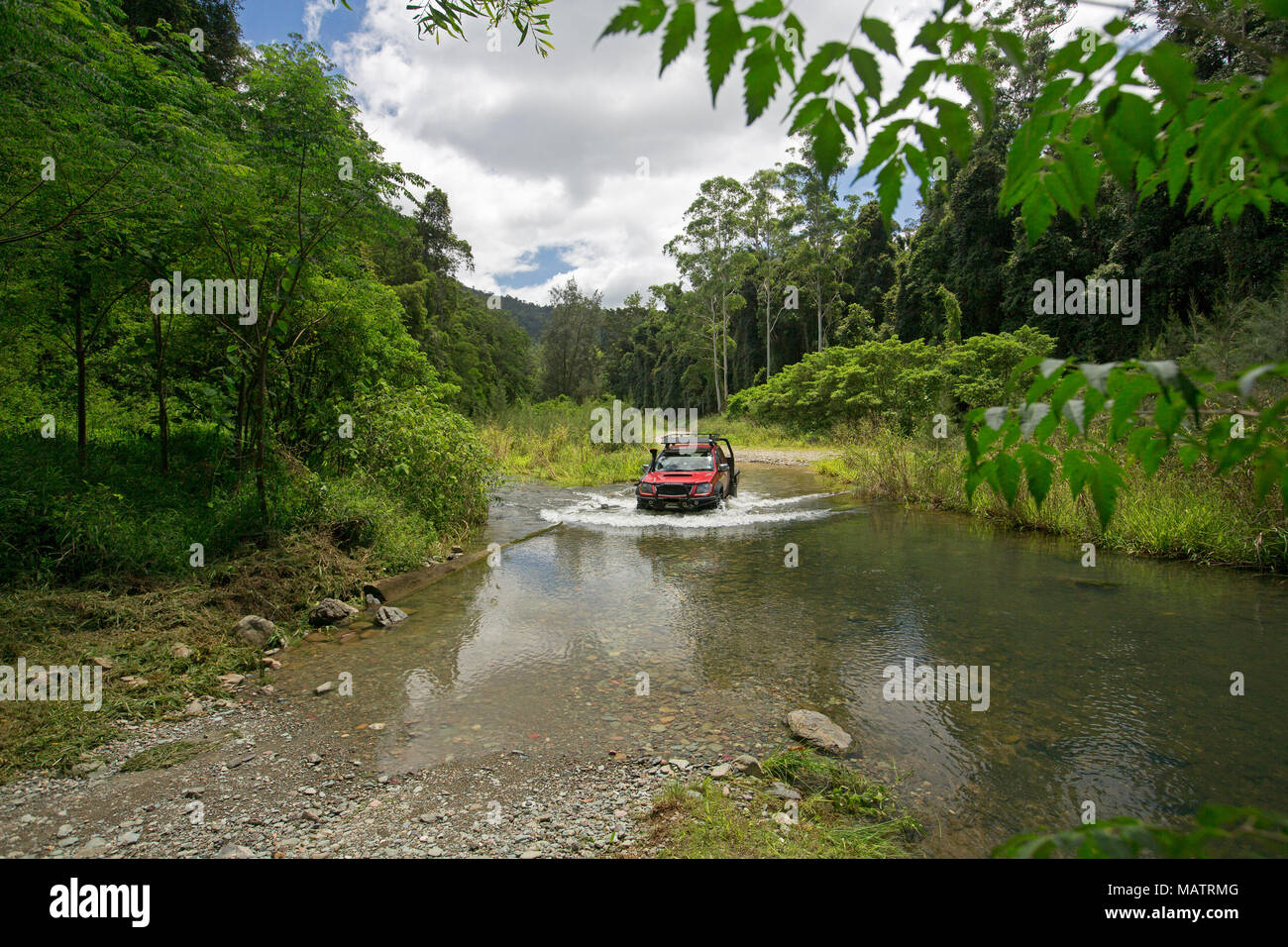 Véhicule à quatre roues motrices rouge crossing creek ourlé à forêts émeraude dans Conondale Queensland Australie Parc National de Banque D'Images