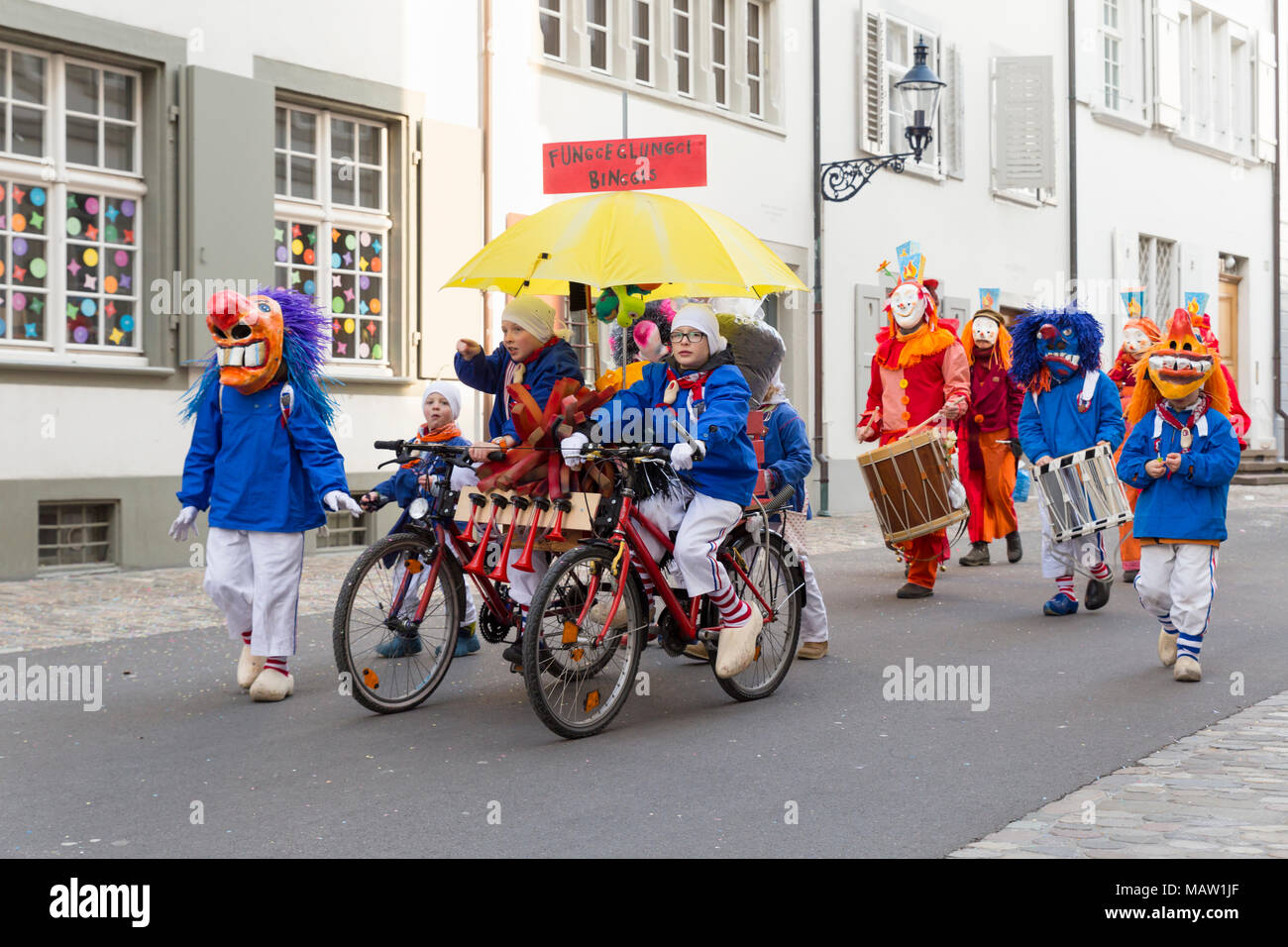 Carnaval de Bâle. Augustinergasse, Bâle, Suisse - 21 février 2018. Groupe d'enfants avec un énorme vélo et costumes colorés Banque D'Images