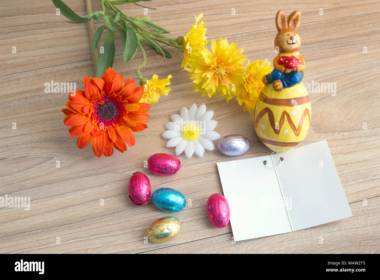 Carte de vœux de Pâques avec les oeufs colorés bonbons, lapin en céramique et des fleurs, sur une table en bois avec copie espace arrière-plan. Banque D'Images Carte de vœux de Pâques avec les oeufs colorés bonbons, lapin en céramique et des fleurs, sur une table en bois avec copie espace arrière-plan. Banque D'Images