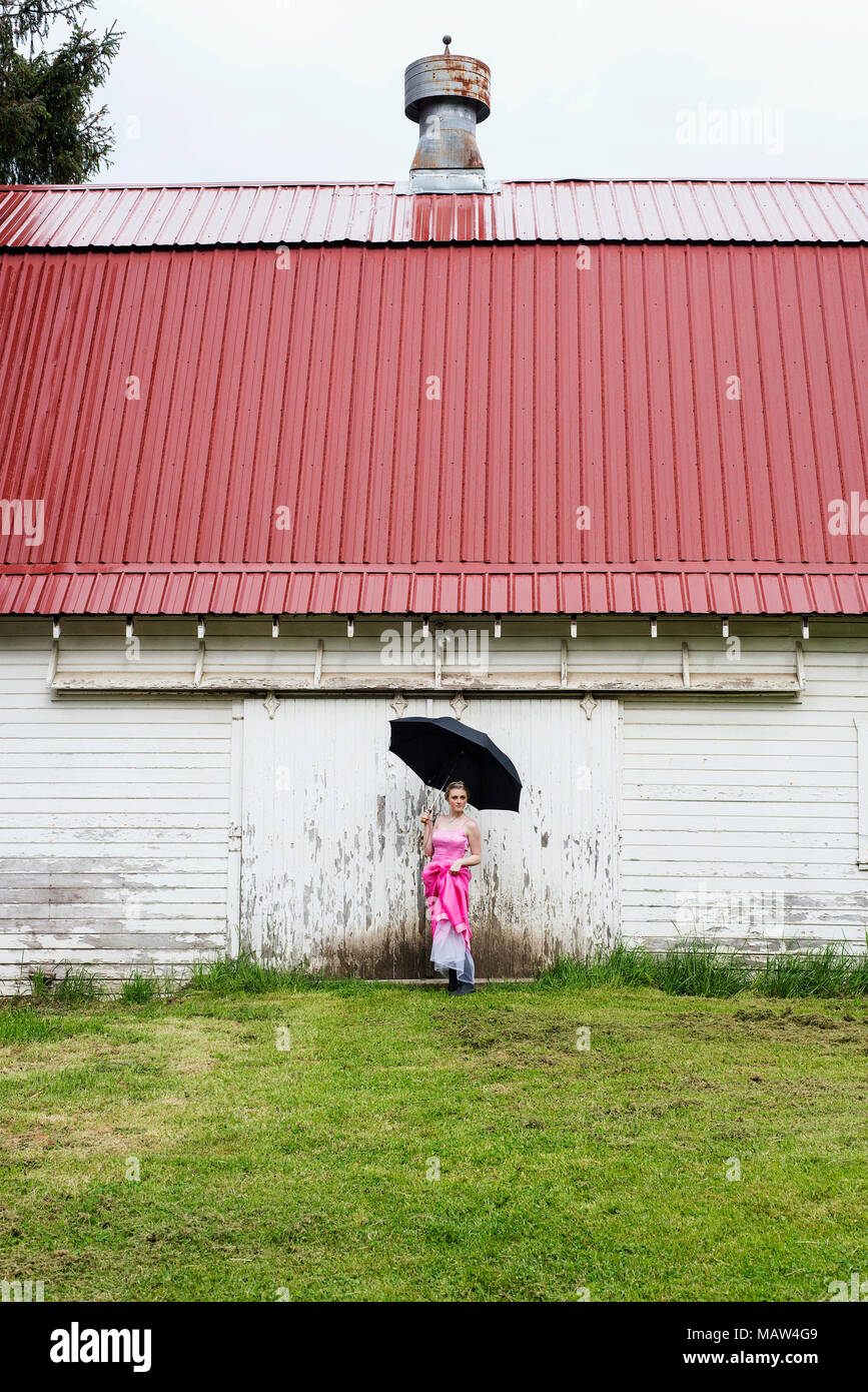Une fille dans une robe rose, debout sous la pluie. Banque D'Images