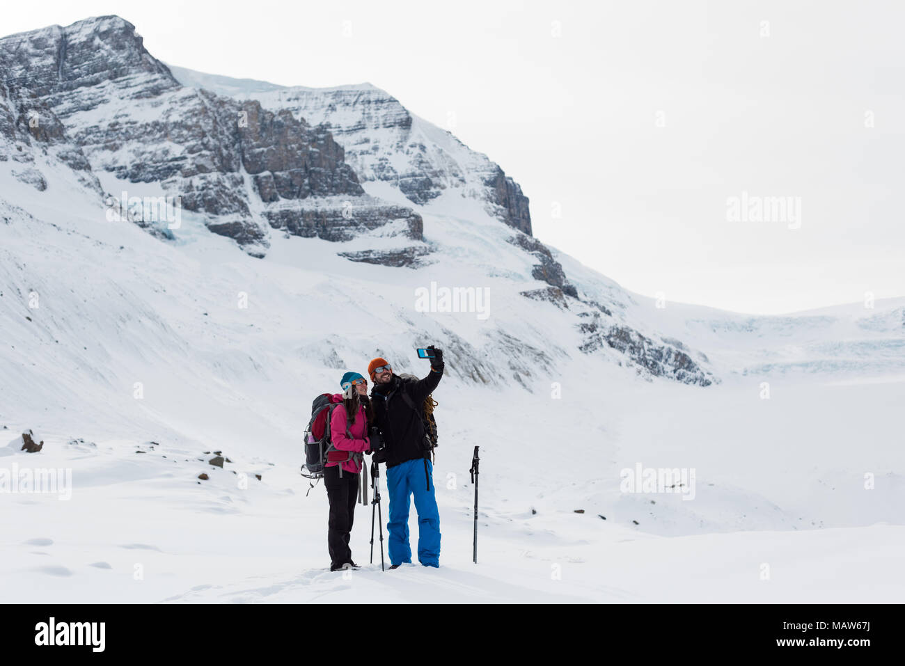 En couple avec selfies téléphone mobile sur une montagne couverte de neige Banque D'Images