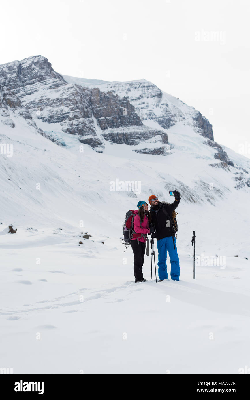 En couple avec selfies téléphone mobile sur une montagne couverte de neige Banque D'Images