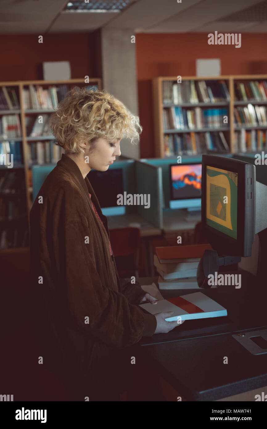 Femme tenant un livre dans la bibliothèque Banque D'Images