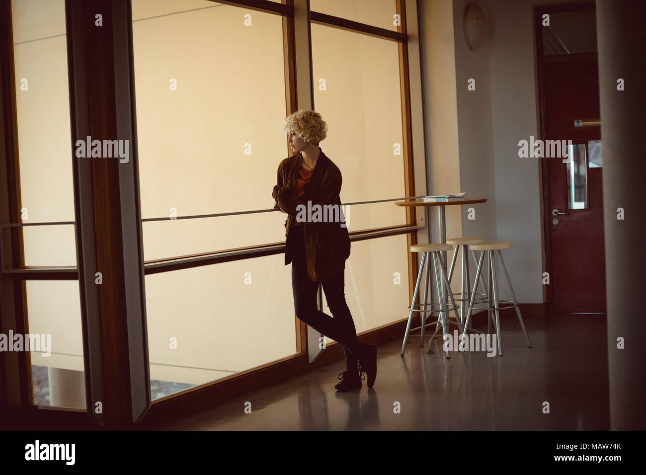 Femme debout près de la fenêtre library Banque D'Images