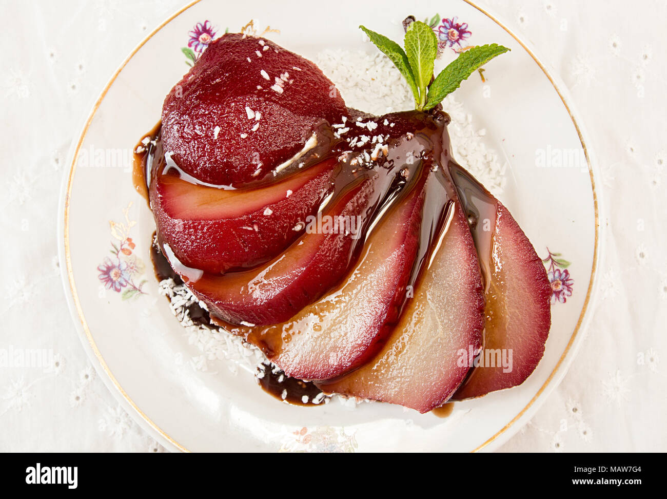 Les Poires au vin. Dessert traditionnel de compote de poires au vin rouge avec une sauce au chocolat sur la plaque sur fond blanc. Vue d'en haut Banque D'Images