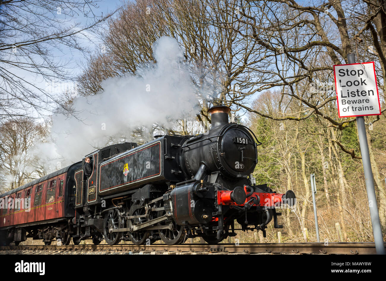 SVR locomotive à vapeur no.1501 soufflant le long à travers la campagne du Worcestershire dans le soleil de printemps. Arrêter de regarder écouter, méfiez-vous des trains signe. Banque D'Images