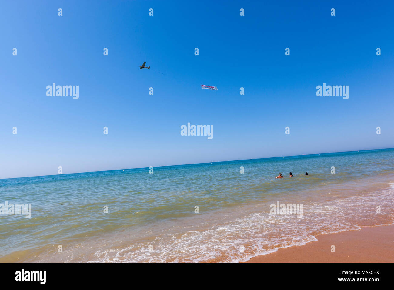 Les baigneurs l'observation d'une publicité plane flying en Parador Mazagon beach, province de Huelva, Andalousie, Espagne Banque D'Images