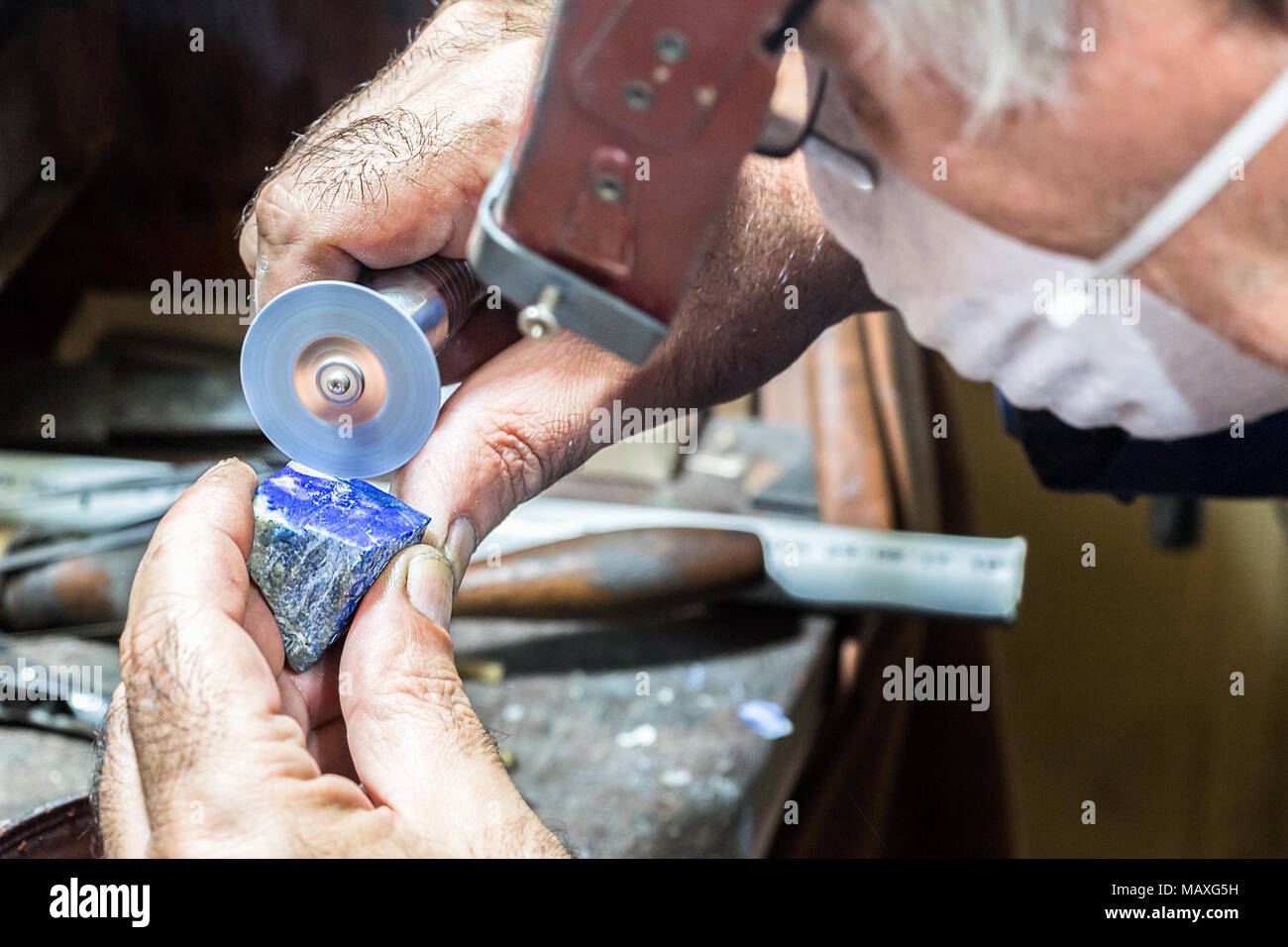 Un port d'un bijoutier loupe pare-soleil de la tête de coupe est une pierre lapis-lazuli avec un disque à tronçonner monté sur un arbre flexible. Banque D'Images