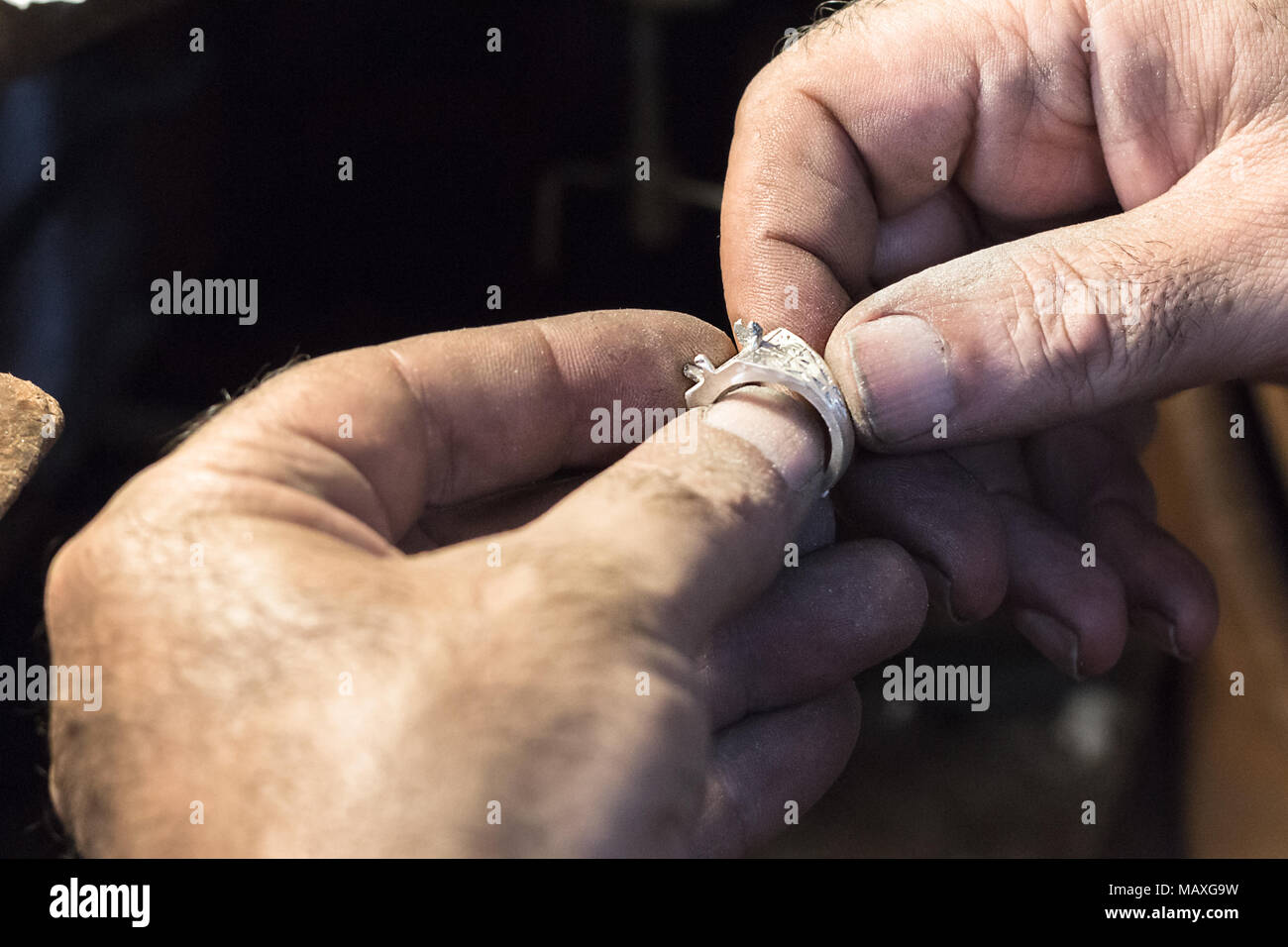 Gros plan des mains d'un bijoutier tenant une bague d'argent. Banque D'Images