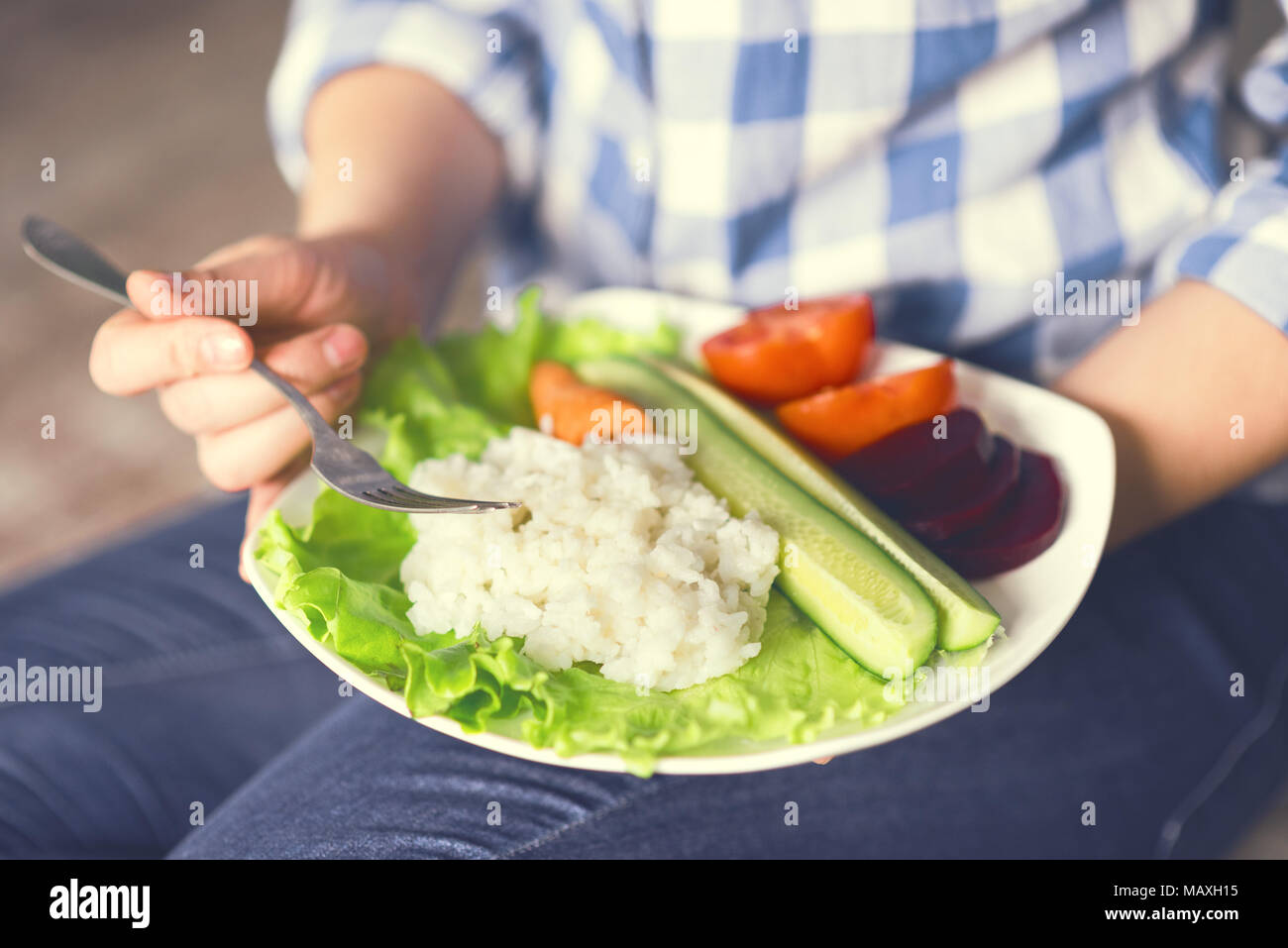 Une fille est titulaire d'une assiette avec du riz et légumes Banque D'Images