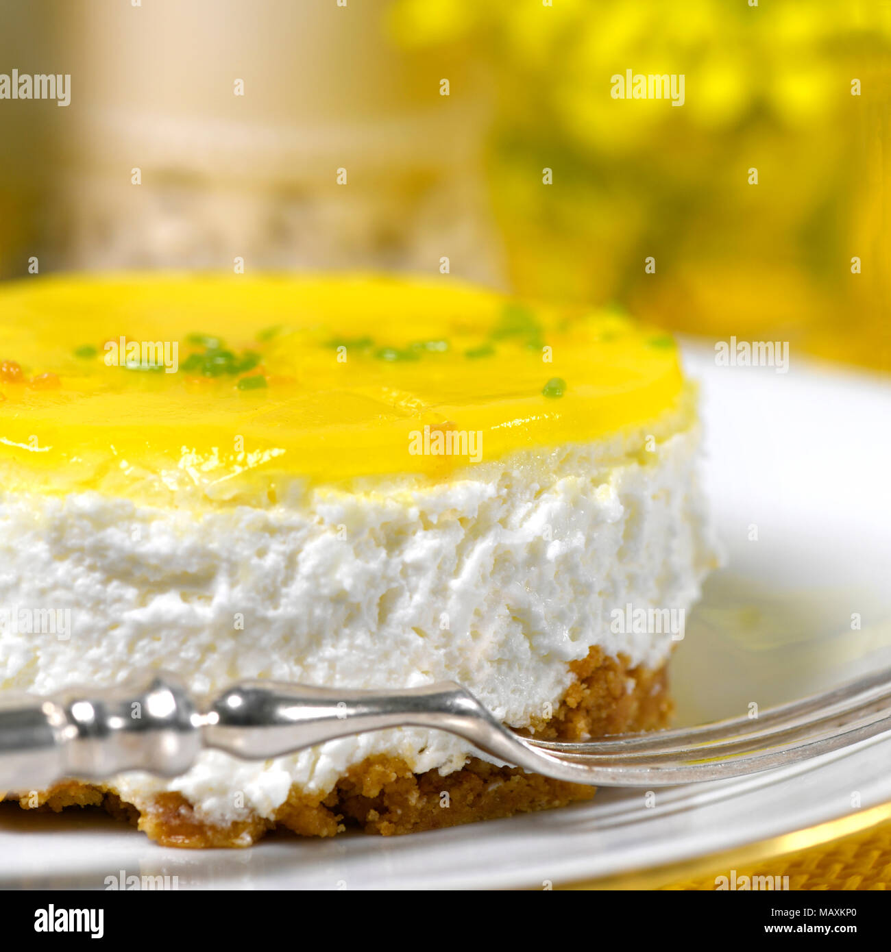 Restaurant d'une mousse au citron cheesecake une fourchette d'argent sur une plaque blanche avec un fond fleurs jaunes et à ad copy space Banque D'Images