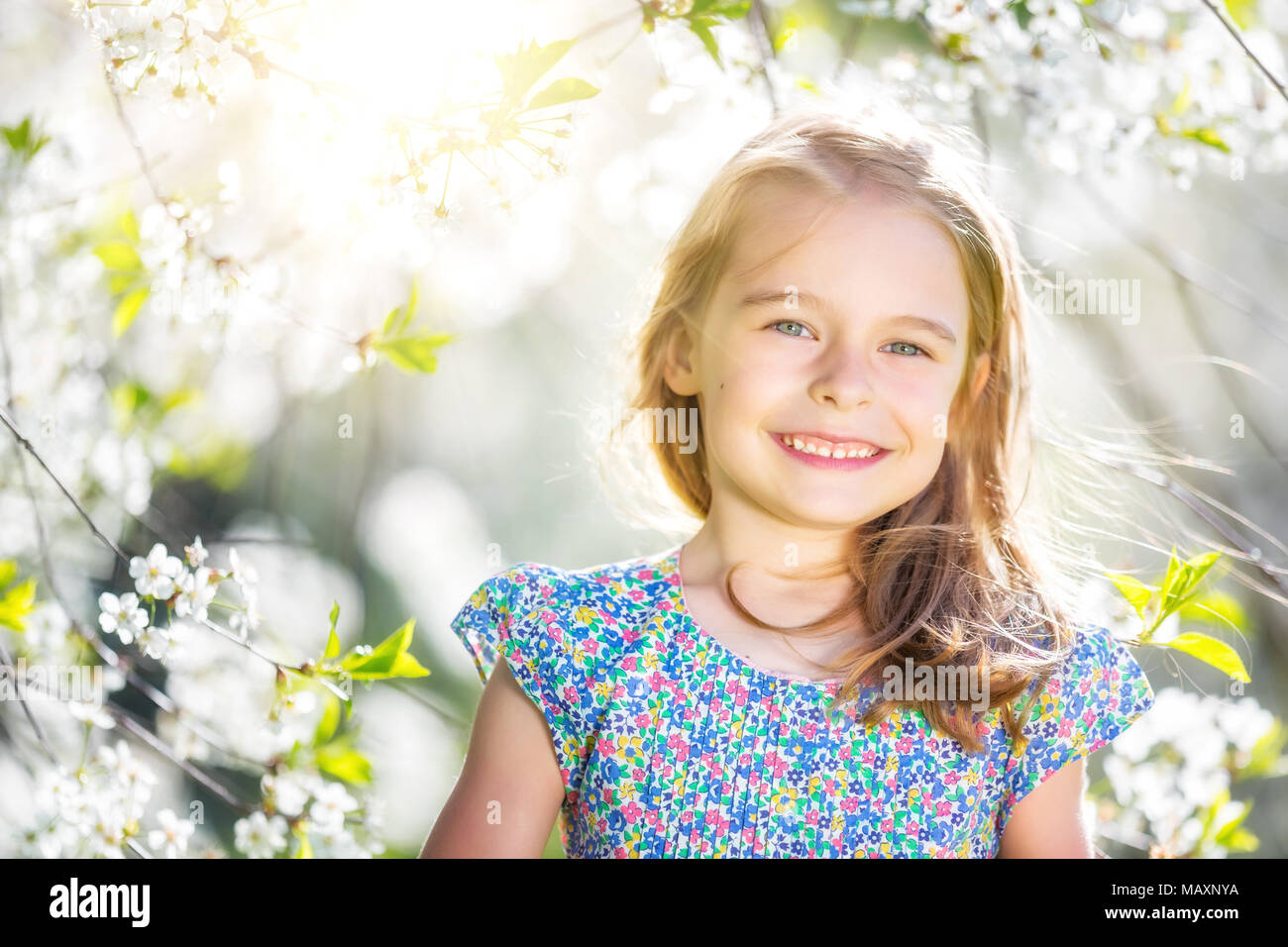 Happy little girl playing in spring cherry garden Banque D'Images
