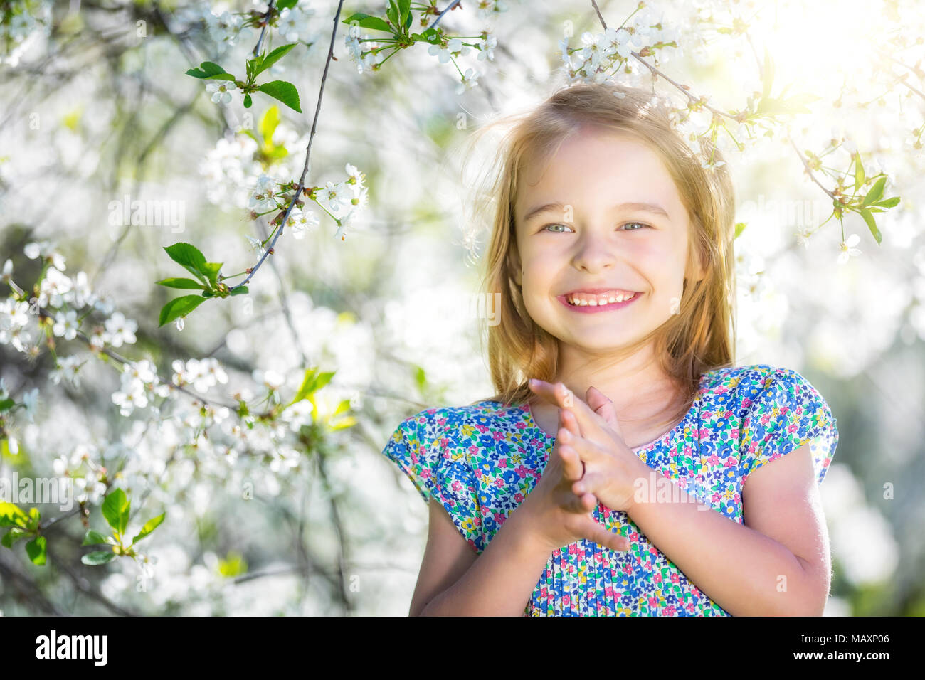 Happy little girl playing in spring cherry garden Banque D'Images