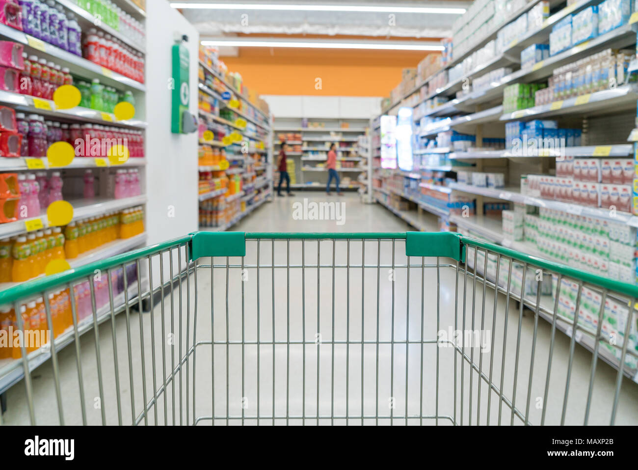 Photo floue abstraite du magasin avec le chariot de magasin à l'arrière-plan flou. Avec l'allée de supermarché vert Panier vide Banque D'Images