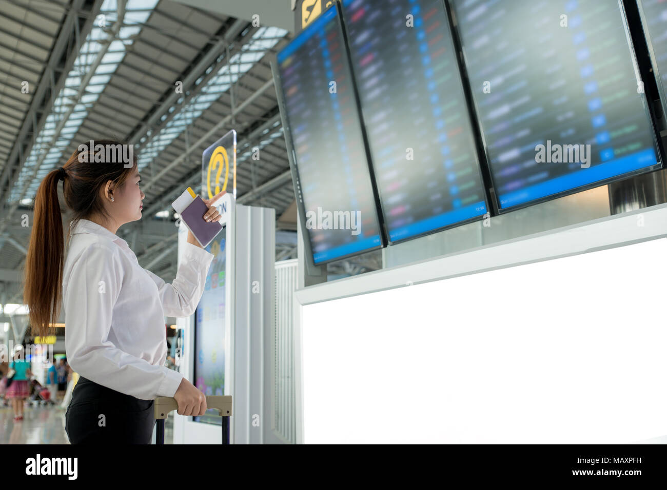 Jeune femme asiatique dans l'aéroport international à la recherche au conseil d'information de vol, contrôle son vol à l'aéroport. Banque D'Images