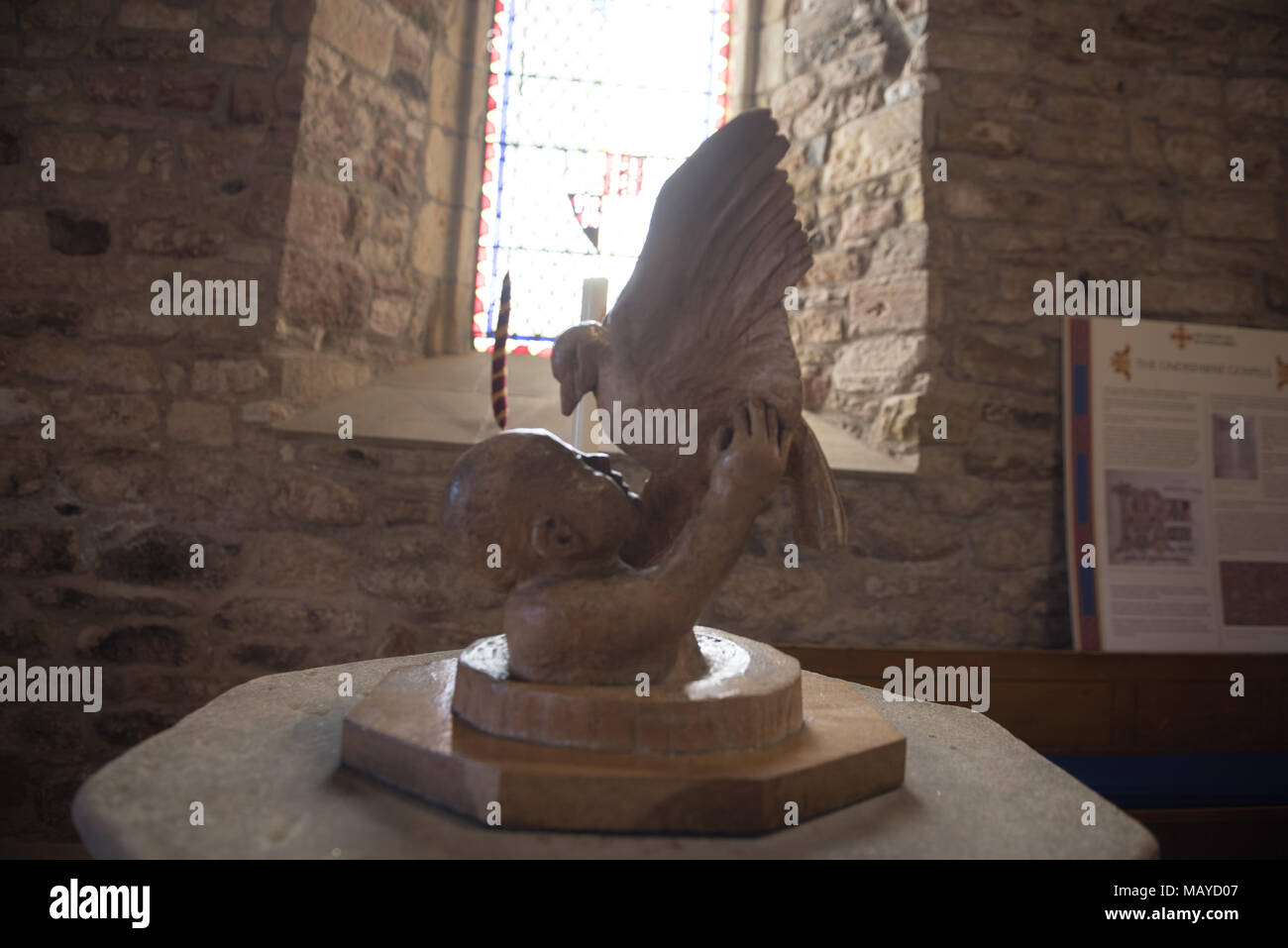 Sculpture de couverture de police à l'intérieur d'une église sur l'île Sainte (Lindisfarne), représentant un enfant soulevant une colombe, éclairé par la lumière de vitraux Banque D'Images
