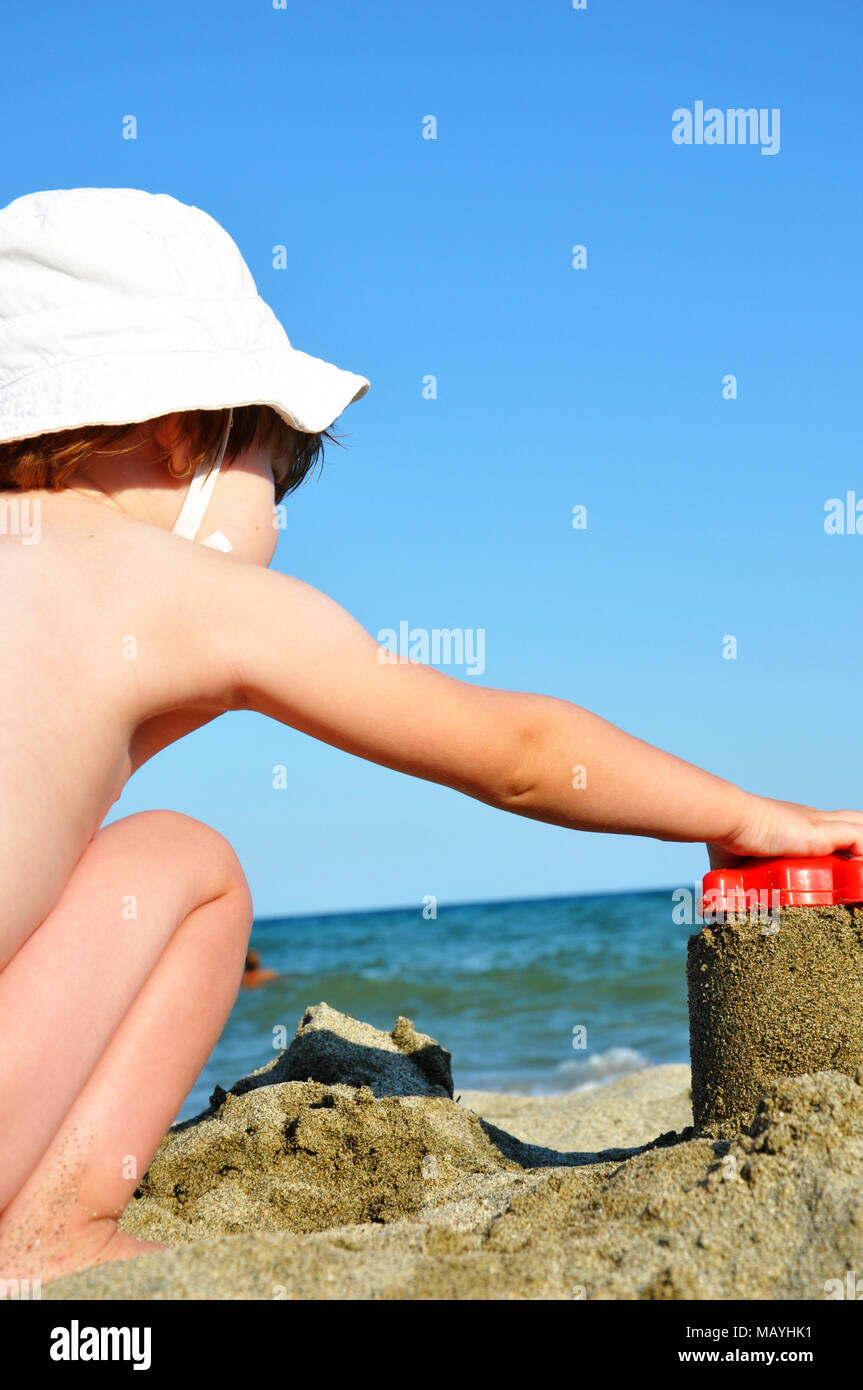Petit enfant, jeune fille, avec chapeau blanc sur la plage de prendre une  forme de sable Photo Stock - Alamy