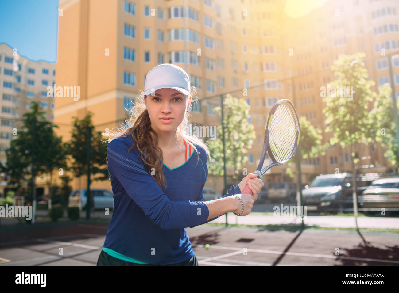 Femme , à la caméra et au holding tennis racket. Joueur de tennis attrayant jouer au tennis piscine,la pratique sur la cour au jour ensoleillé, sur une ville b Banque D'Images