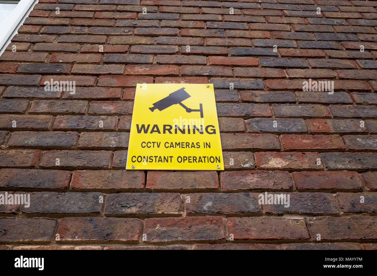 Les caméras de vidéosurveillance d'avertissement en signe sur mur de briques, UK Banque D'Images