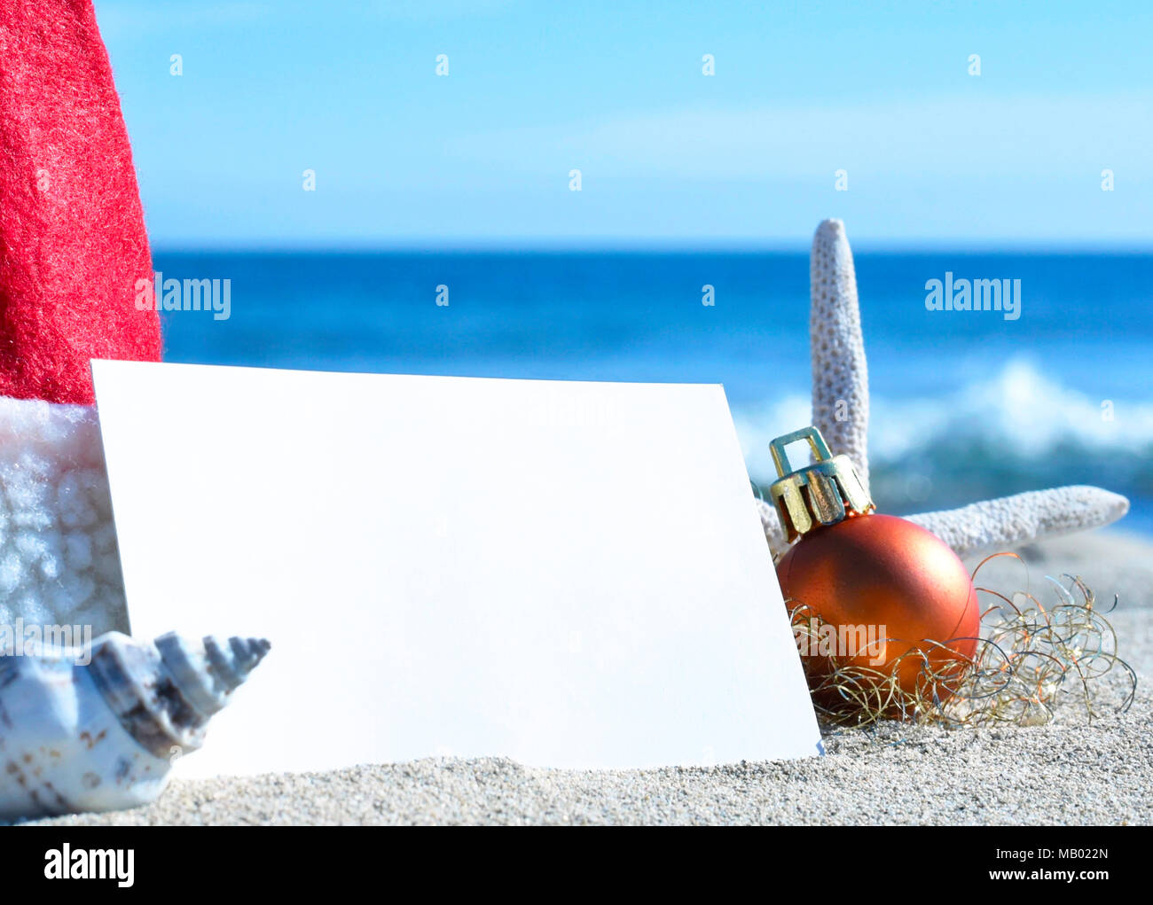 Carte de vœux de Noël et de décoration de Noël sur la plage. Scène de plage avec des étoiles de mer, coquillages et sable. Christmas Tree ball vierge et carte blanche. Banque D'Images