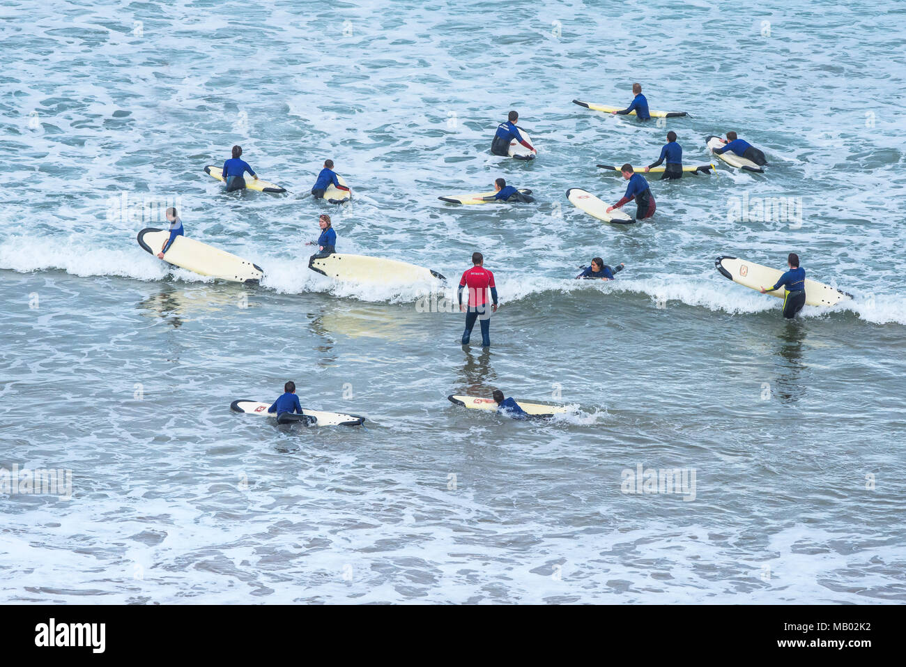 Les jeunes bénéficiant d'apprendre à surfer avec l'aide d'un instructeur de surf à Newquay en Cornouailles. Banque D'Images