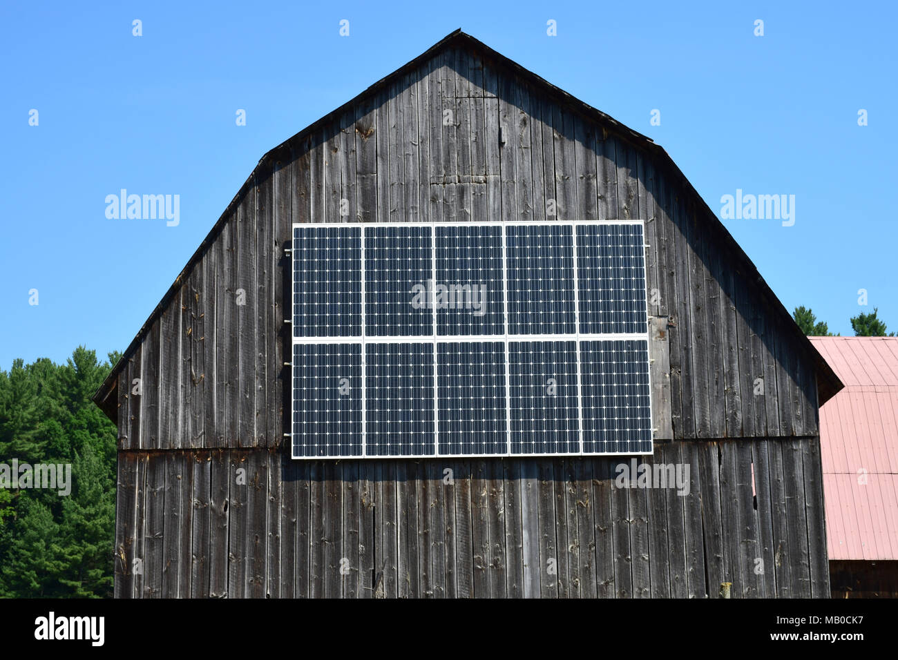 Une ancienne grange en bois avec panneaux solaires. Banque D'Images
