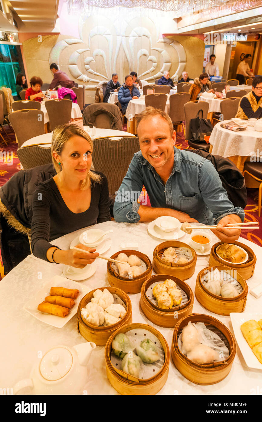 La Chine, Hong Kong, Tourist Couple Eating Dim Sum Banque D'Images
